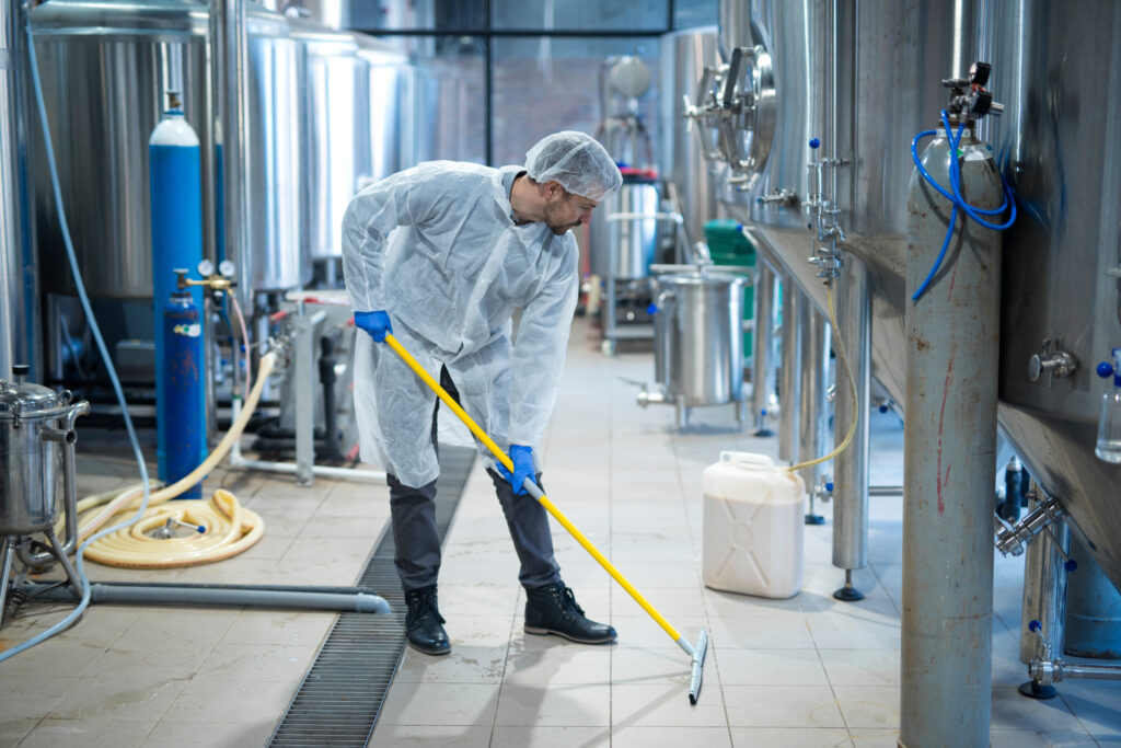 Worker in protective gear mopping a commercial food production floor